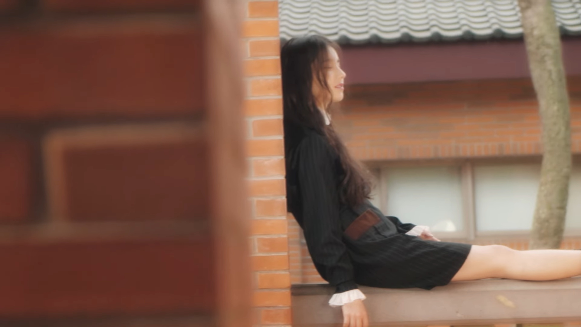 Heejin resting against a wall.